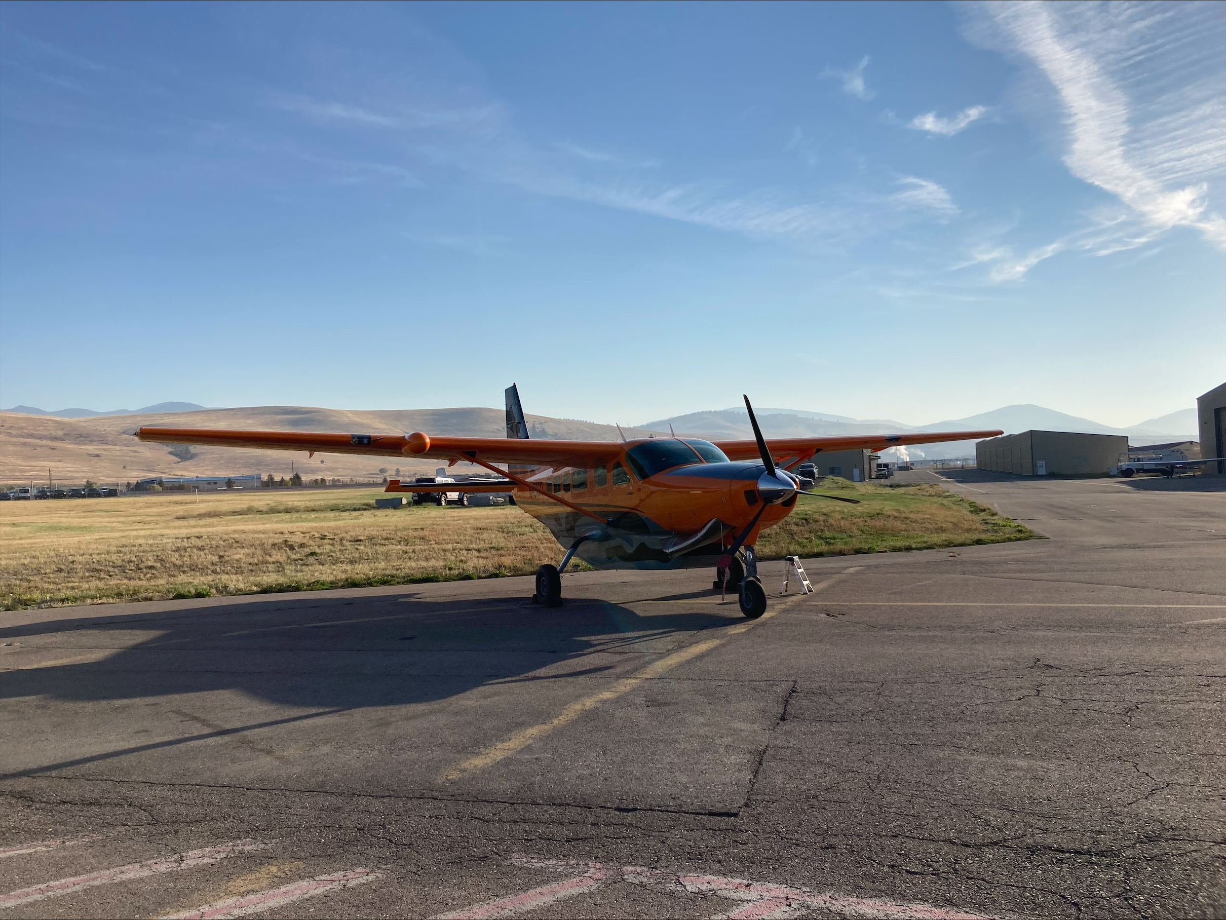 Orange Cessna Caravan parked at a mountain airport